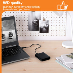 Western Digital reliable backup storage device connected to laptop on wooden desk with photos and books