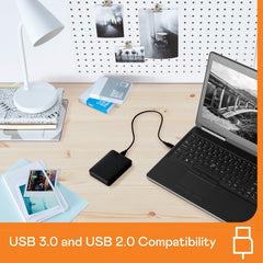 Western Digital reliable backup storage device connected to laptop on desk with photos and lamp