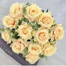 Artificial bouquet of pale cream roses with peach centers and small green filler leaves
