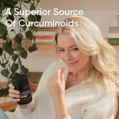 Woman holding Sports Research bottle and capsule of turmeric curcumin supplement UAE for joint and inflammation support