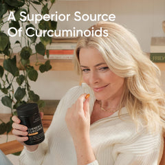 Woman holding Sports Research bottle and capsule of turmeric curcumin supplement UAE for joint and inflammation support