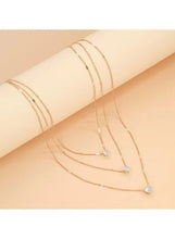 Gold three-layer charm necklace on arm with layered crystal drop strands