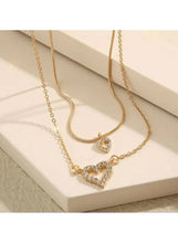 Gold-tone layered heart pendant necklace with crystal heart charms on two chains