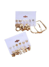 Earrings set on cards with gold hoops, pearls, and crystal geometric studs