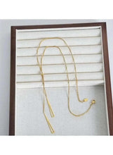 Gold-tone triangle pendant necklace on display stand with two long hanging drops