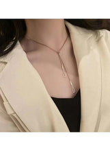 Gold-tone triangle pendant necklace worn with thin chain and two slim drops