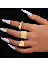 Gold-tone rings on hand with glossy wide cuff and two textured open bands, stacked look