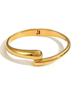 Gold tone wave cuff bracelet with smooth twisted front and hinged clasp