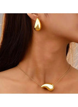 Gold-tone waterdrop necklace and stud earrings on model, glossy teardrop jewelry