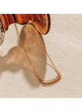Gold tone crescent pendant necklace with cubic stone bar trim
