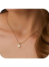 Gold pendant necklace on neckline, round crystal center charm
