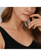 Gold pendant necklace with round crystal charm resting at collarbone