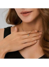 Gold pendant necklace with round crystal pendant held near the collar
