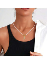 White pearl beaded necklace with gold initial charm on a fine chain