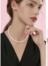 White pearl necklace choker length worn on model, smooth round beads