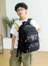 Black printed school trolley backpack worn by a child, front zipper pockets and wheels