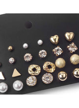 Gold-tone earring studs close-up: heart, crystal, pearl and textured sphere styles