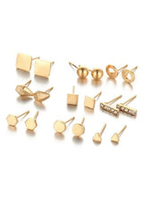 Gold stud earrings set with assorted geometric and circular designs, flat lay