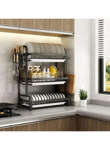 Black dish drying rack mounted on wall, showing two-tier drying shelves for plates