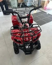 Red electric ATV quad bike with black front rack and seat, shown indoors