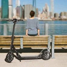 Black kick scooter with rider seated, wheels and deck visible