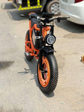 Front view of orange electric bike with black fork and wide tread tire.