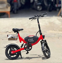 Red foldable electric bike with front basket, black saddle, and kickstand