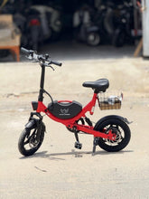 Red foldable electric bike with front basket, black fenders, and upright kickstand