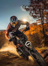 Rider on an electric fat-tire bike kicking up dust on an off-road trail with headlight on.