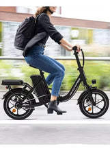 Black folding electric scooter with headlight and front disc brake, rider in motion.