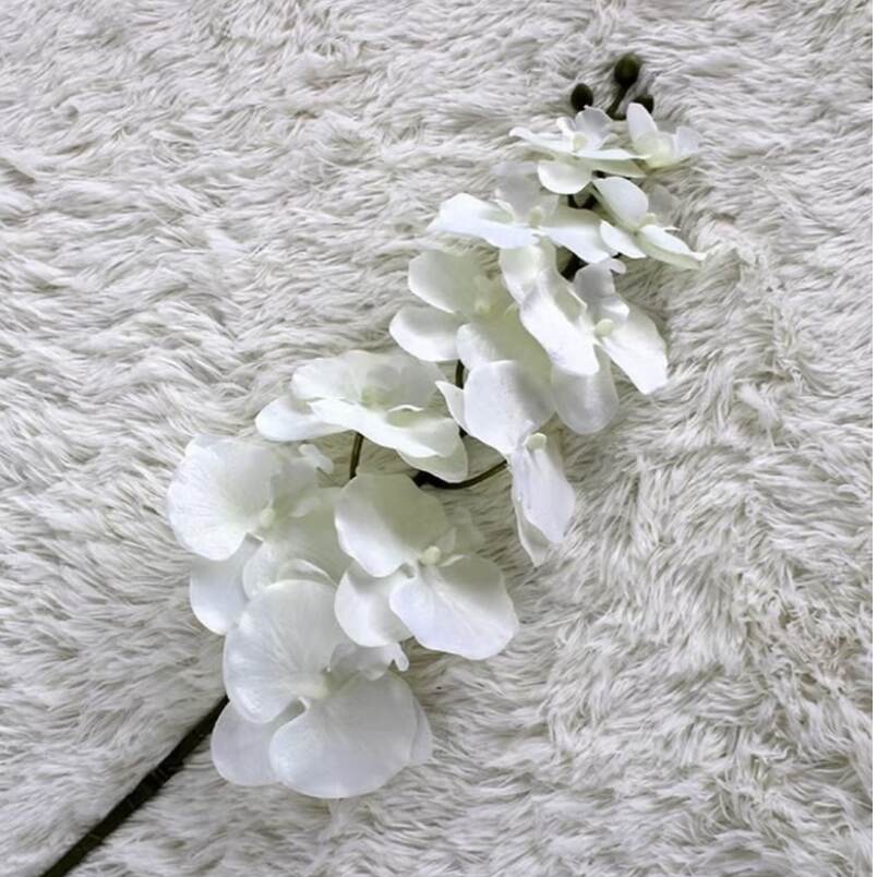 Huitich white artificial dendrobium flowers on a soft textured surface