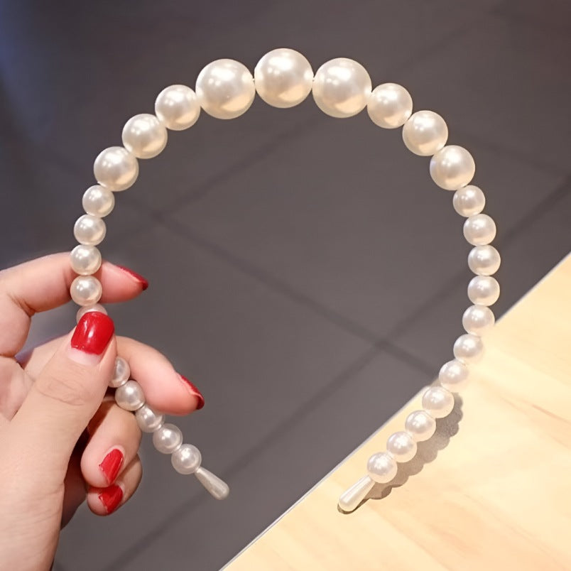 Huitich white pearl hair accessory headband with graduated pearl beads held by hand