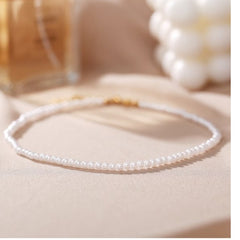 Huitich elegant white pearl necklace for women with small pearls and gold clasp on beige background