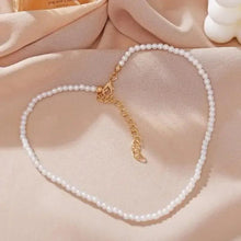 White pearl necklace with gold chain and small gold charm