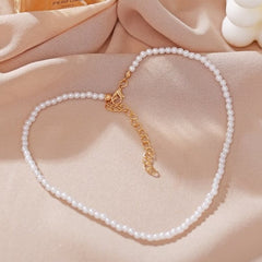 Huitich white pearl necklace for women with gold clasp laid on soft beige fabric