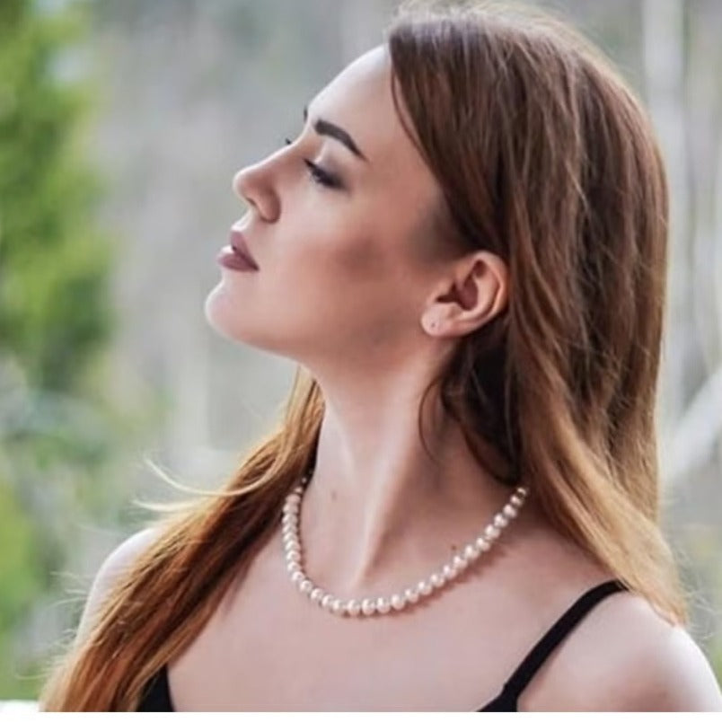 Woman wearing Huitich white pearl necklace for women with natural background and long hair