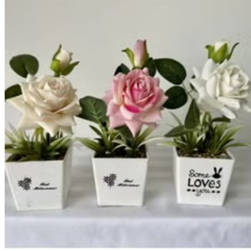 Three artificial flowers in white pots including a pink rose and artificial purple rose plant by Huitich