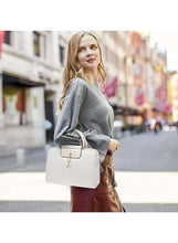 White PU leather mini handbag with top handle, front clasp flap, and dangling charm