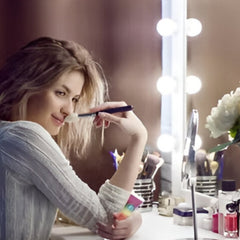 Woman holding Huitich rainbow lip gloss applying makeup at vanity mirror with lights