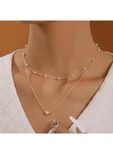 Gold-tone layered necklace with faux pearls and heart pendant worn at neckline