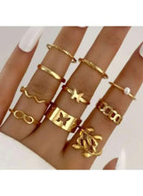 Gold-tone mixed design ring set with charms and pearl detail, stacked on hand
