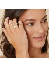 Gold-tone ring set with white accents on hand, stacked minimal bands
