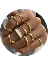 Gold-tone ring set with white accents on fingers, stacked minimal bands close-up