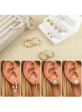 Gold-tone earrings worn on ear: small hoops, pearl drops, and heart charm studs
