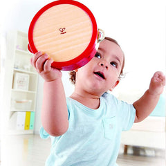 Toddler playing with red wooden tambourine from wooden music set for kids by Huitich