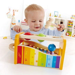 Baby playing with colorful wooden music set for kids including xylophone and hammer toy