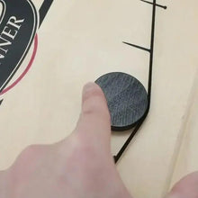 Wooden puck game board with a hand placing a dark round puck on a line