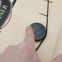 Hand flicking black wooden puck on a wooden puck game board by Huitich for learning and education