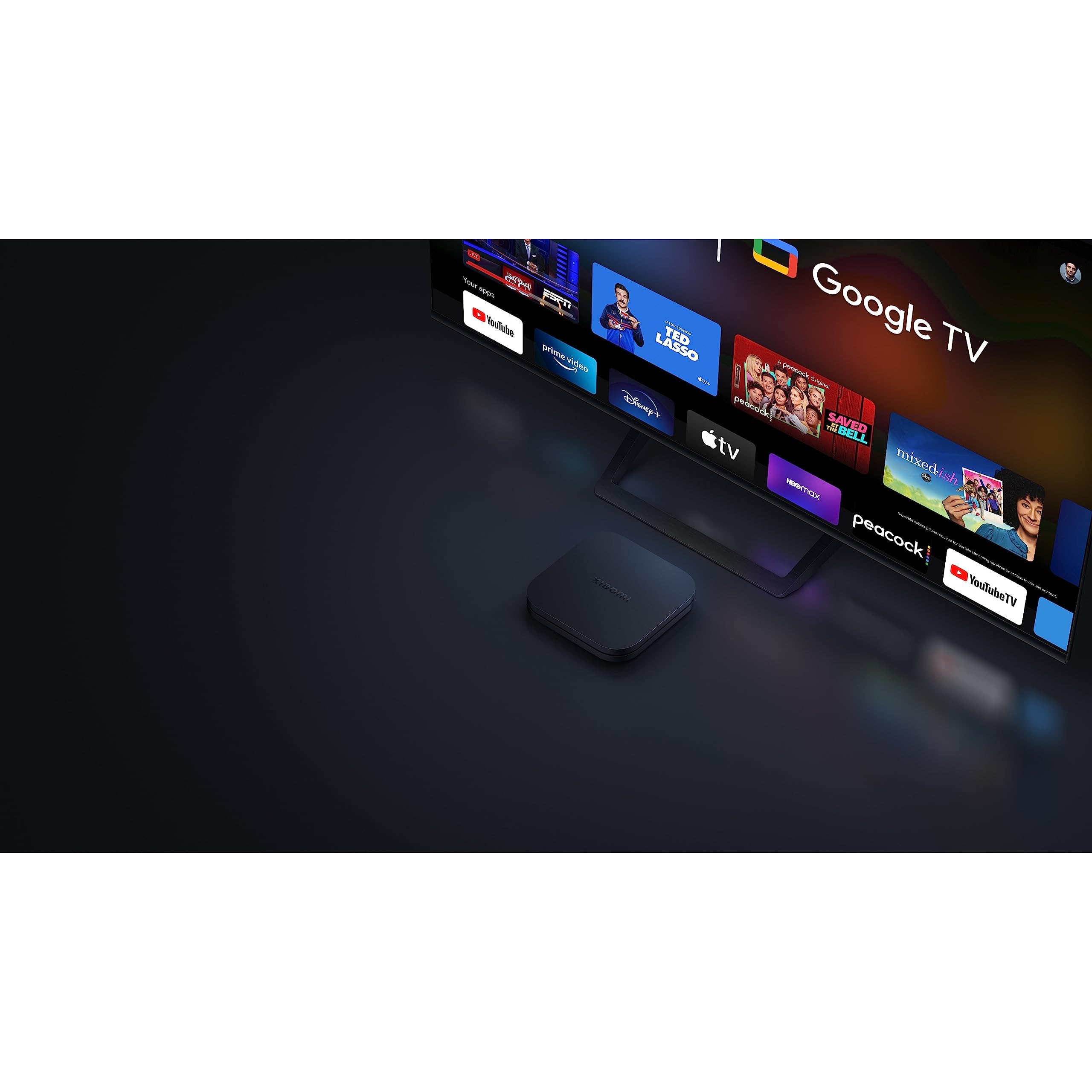 Xiaomi Mi Box S 2nd Gen 4K streaming device placed in front of a TV displaying Google TV interface