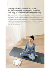 Xiaomi smart body scale on floor in home setting, white glass with four sensors
